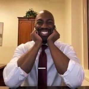 Man in shirt and tie resting his face in his hands, beaming a huge delighted grin