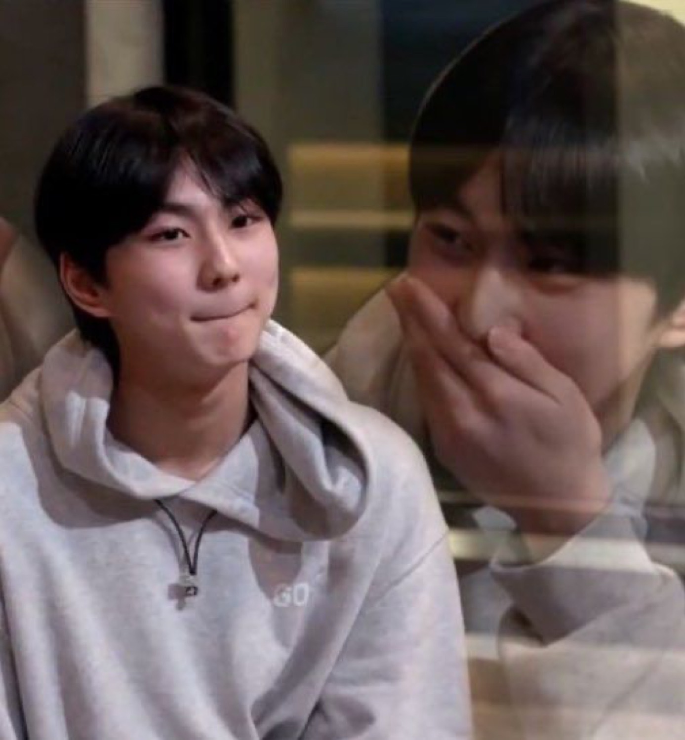 Guy in a grey hoodie pressing his lips together in a smug little half-smile