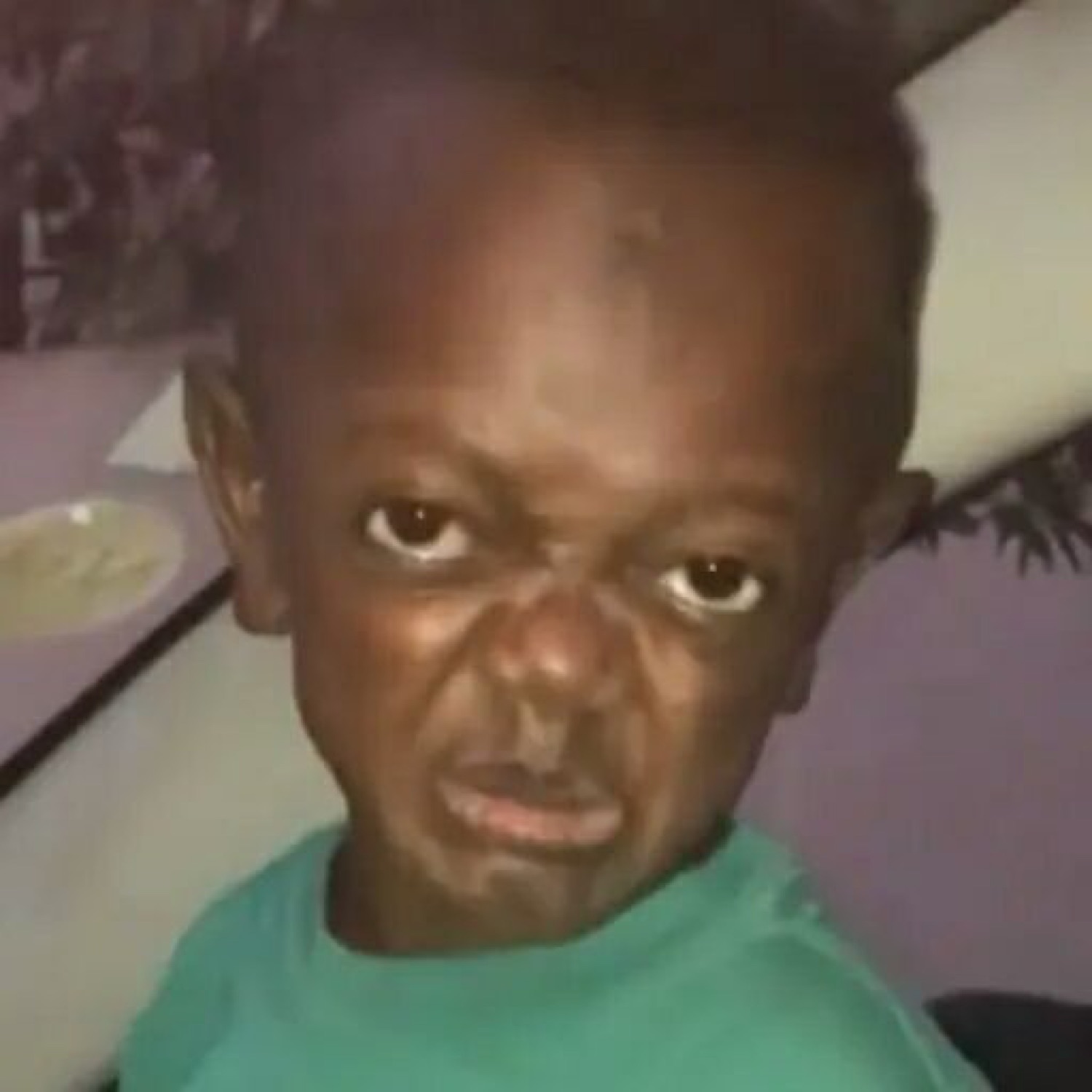 Young child with a deeply furrowed brow and a scowling glare directed straight at the camera