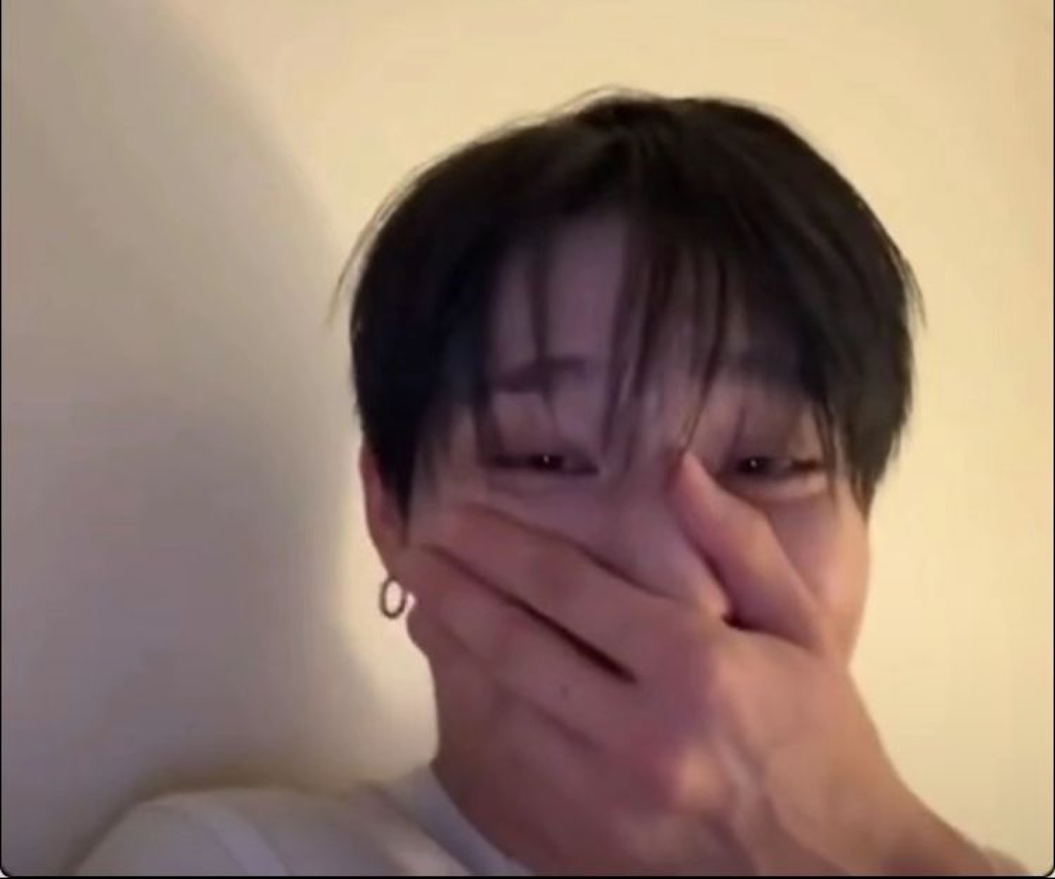 Young man covering his mouth with his hand, laughing shyly