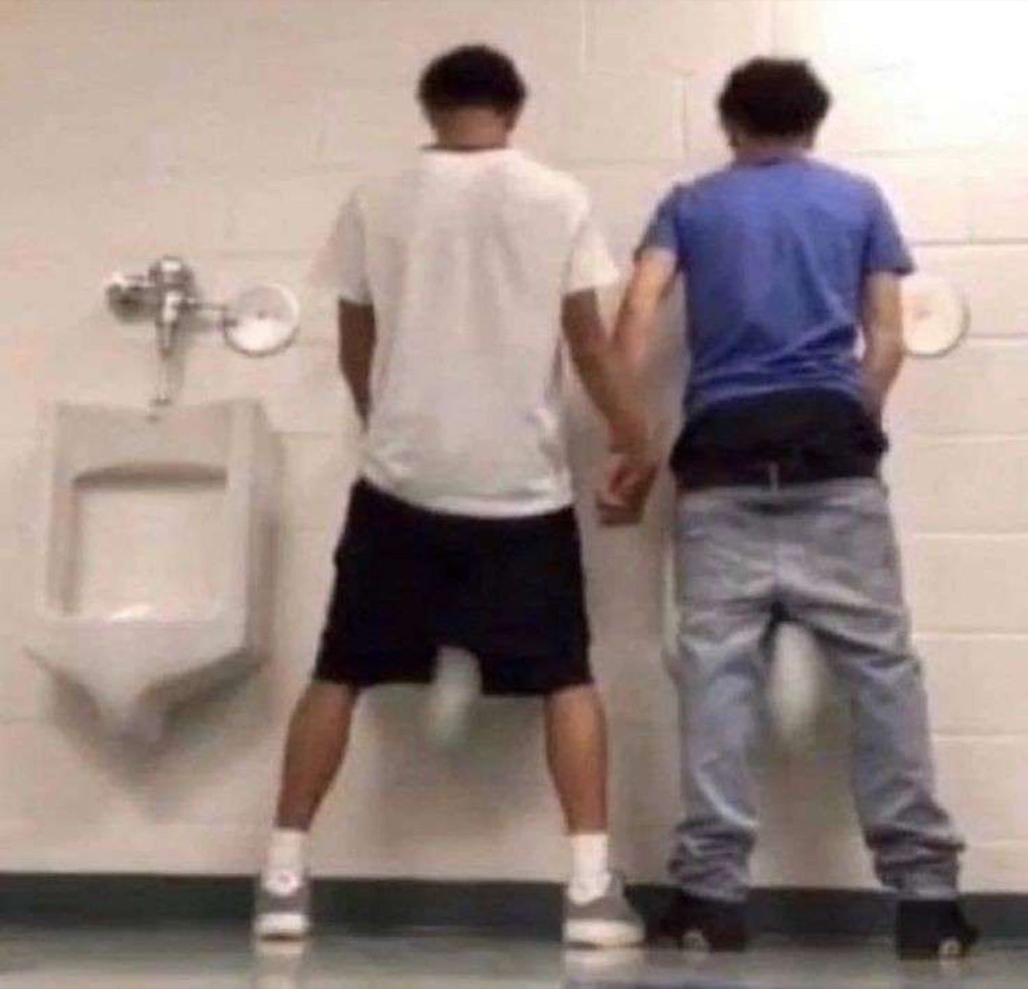 Two guys holding hands at the urinals, not quite the usual bathroom situation