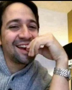 Man laughing hard with chin resting on his hand, eyes crinkled with joy
