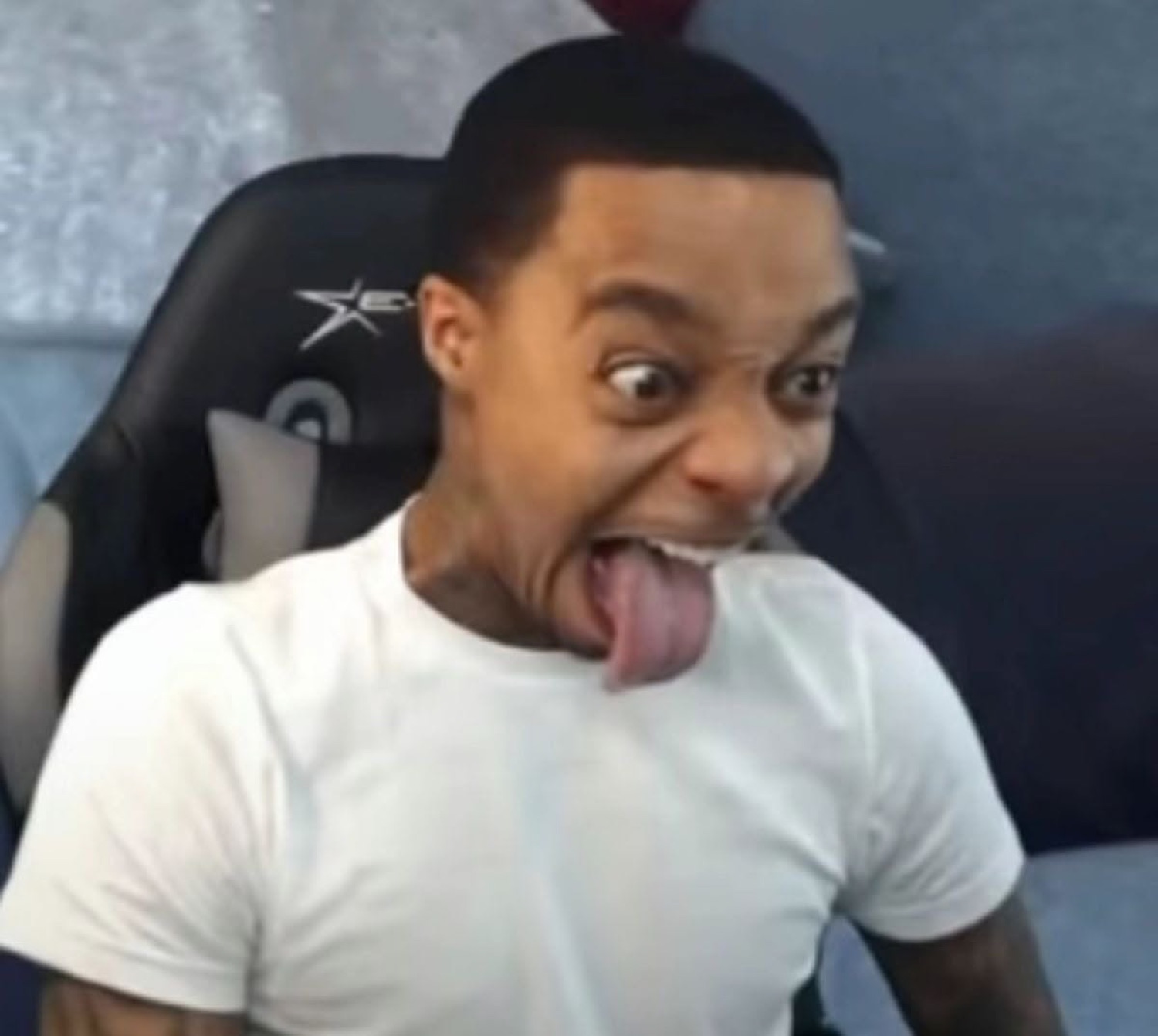 Man in a gaming chair pulling a wild goofy face with his tongue stretched out