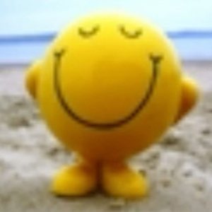 Mr. Happy smiley face toy on a beach with eyes closed and a calm contented smile