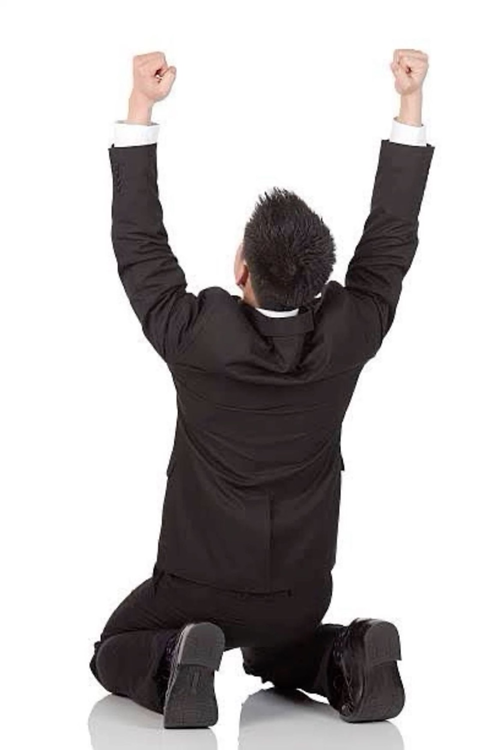 Man in a black suit kneeling with both fists raised in a triumphant victory pose