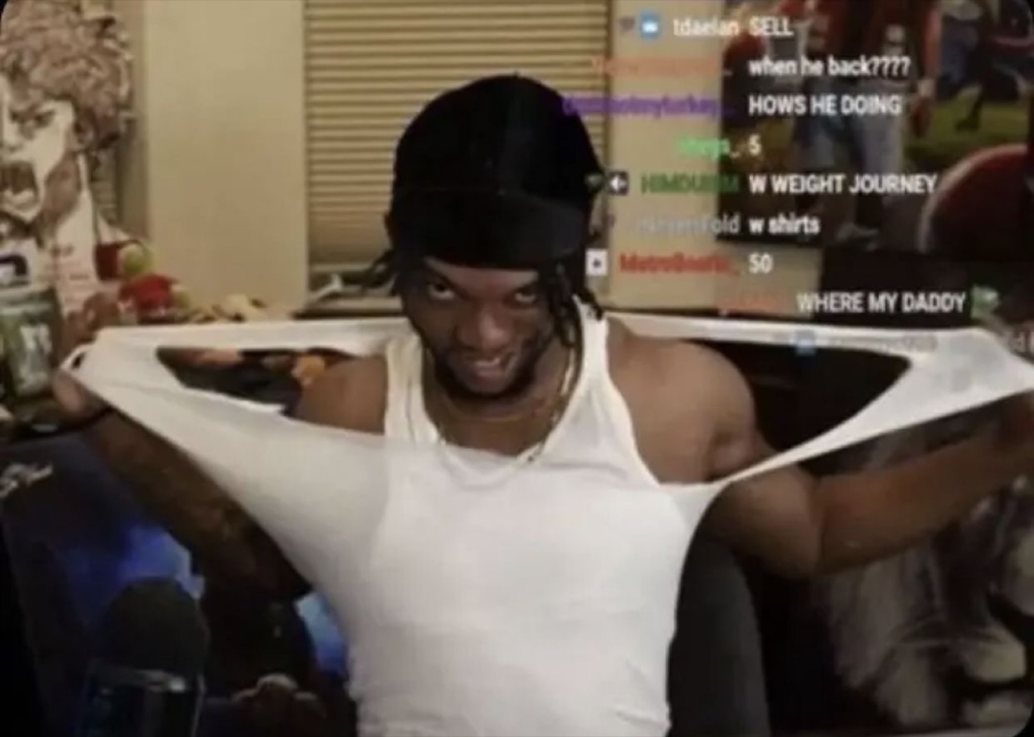 Streamer in a durag stretching his tank top with a wild grin as chat spams him