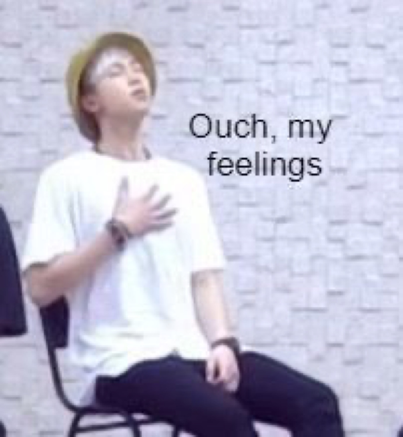 Young man in a yellow bucket hat clutching his chest with eyes closed, 'Ouch, my feelings'