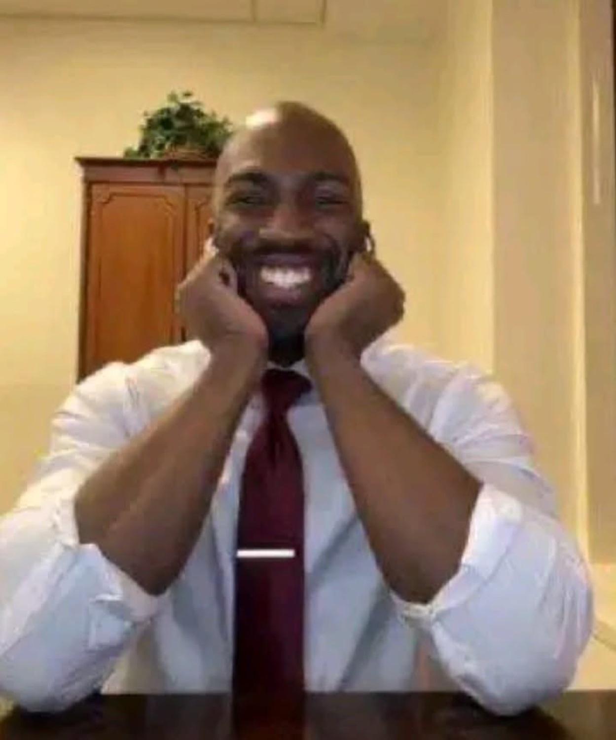 Dressed-up man resting his face in his hands with the biggest, most delighted grin