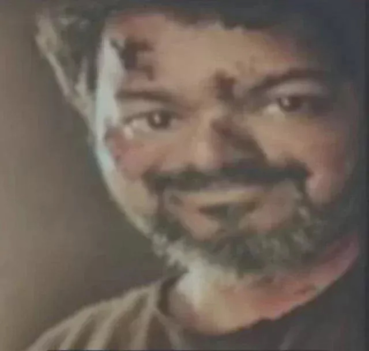 Bearded Vijay with a sly grin in shadow