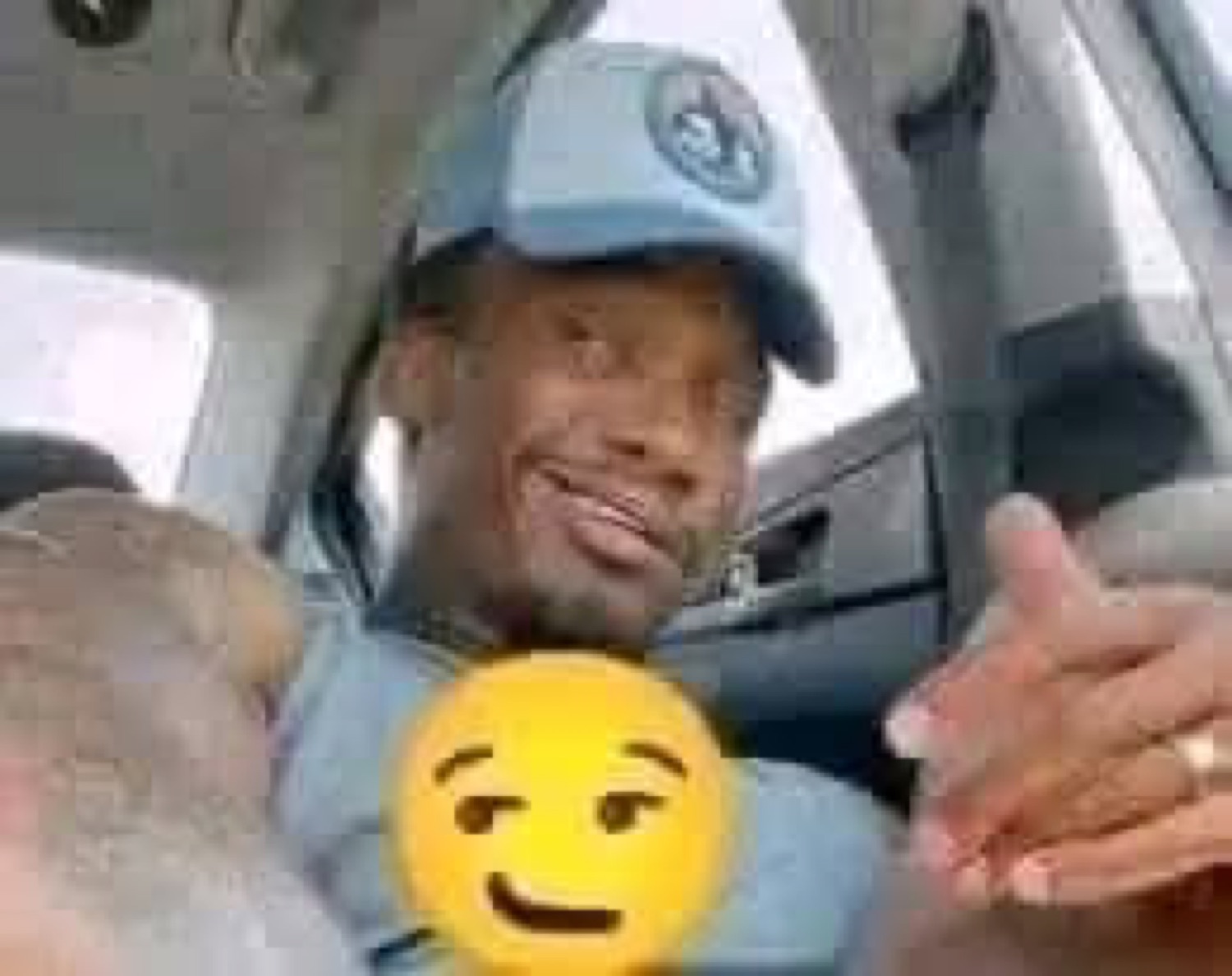 Man in a car cap grinning with a smirking emoji over his chest