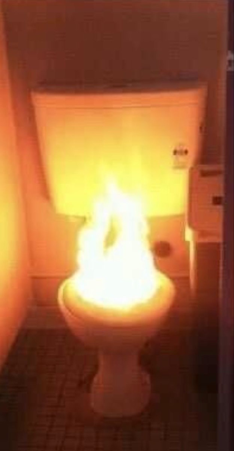 Toilet bowl on fire in a dark bathroom