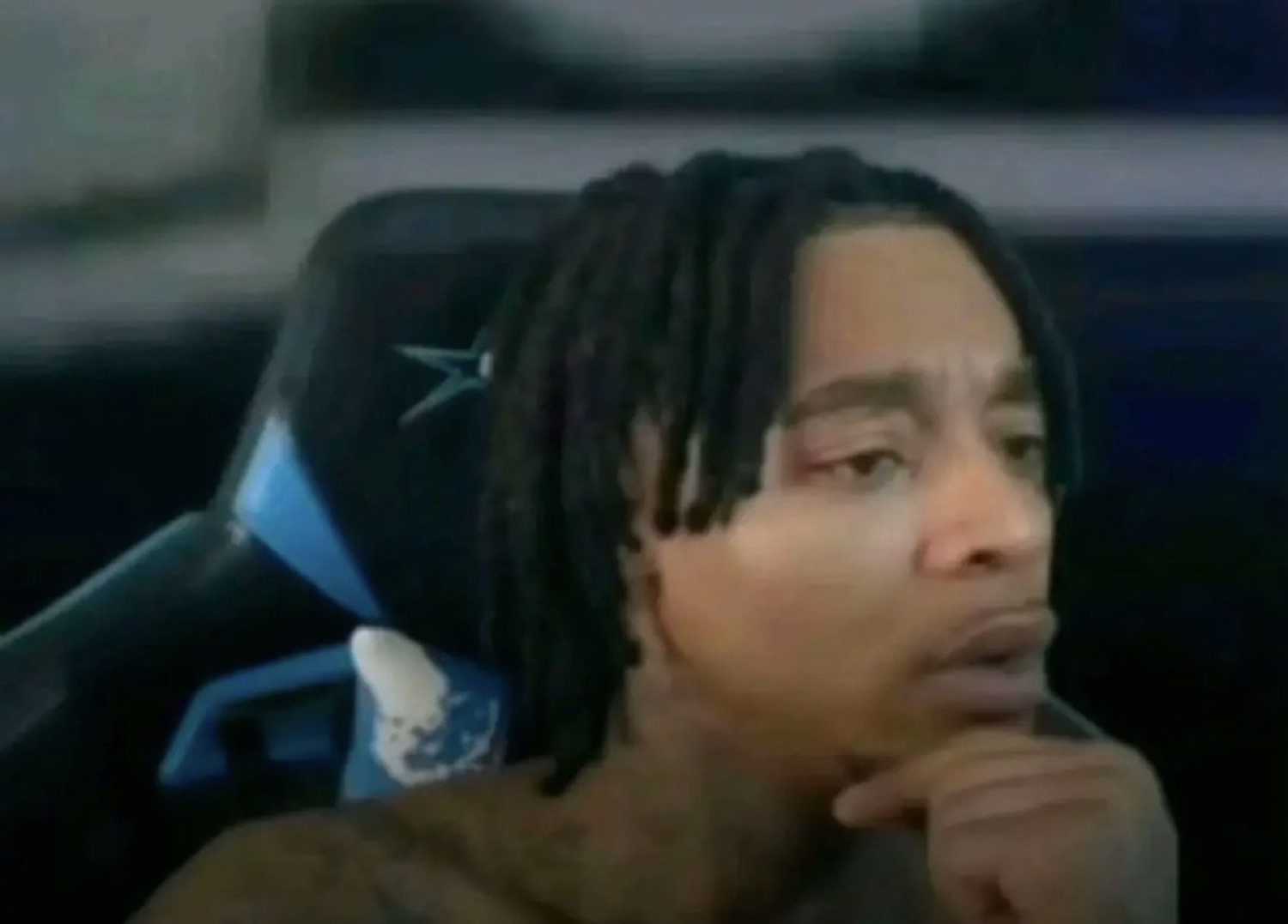 Guy in a gaming chair resting his chin, giving a skeptical sideways look