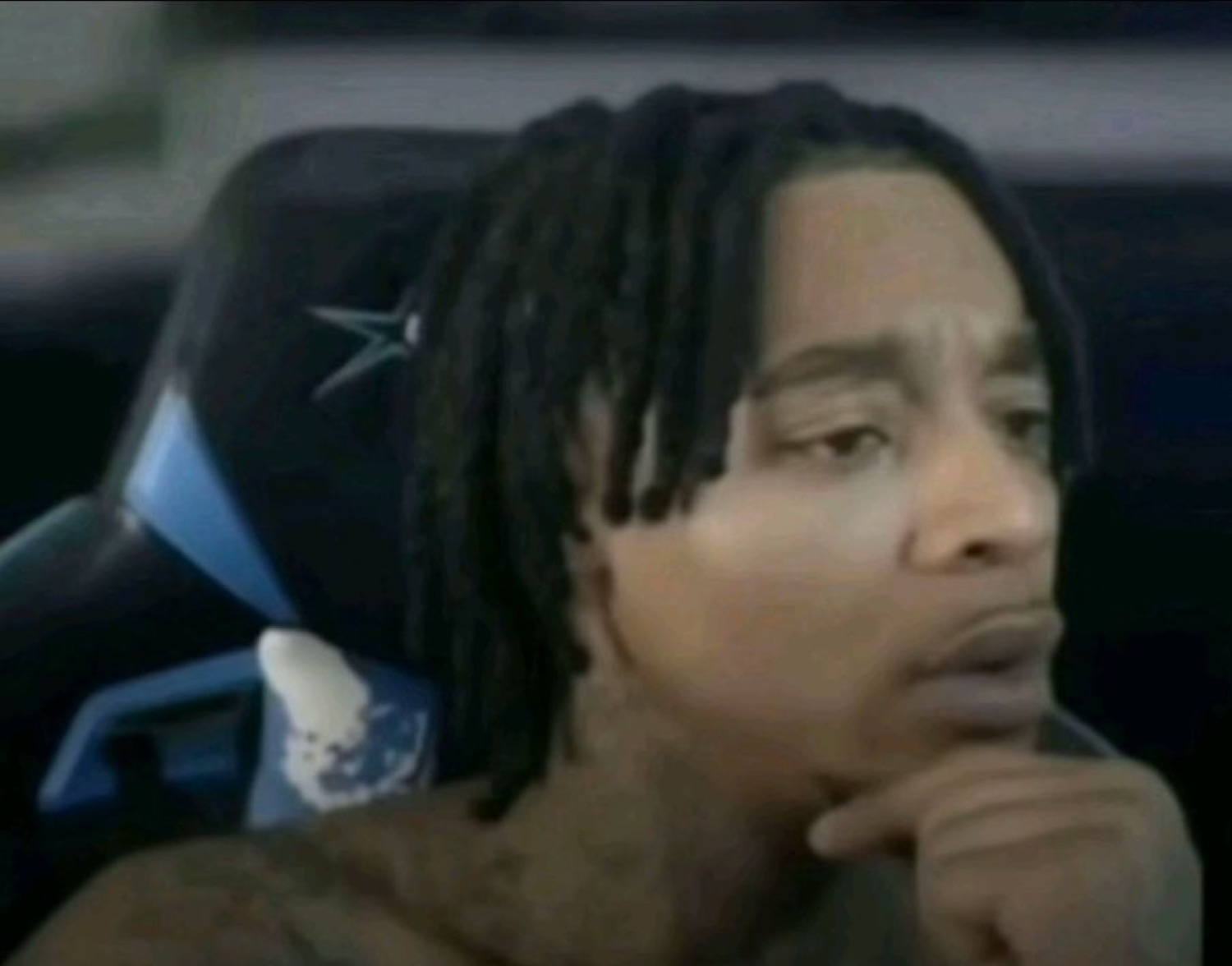 Guy in a gaming chair resting his chin on his hand with a skeptical, thoughtful look