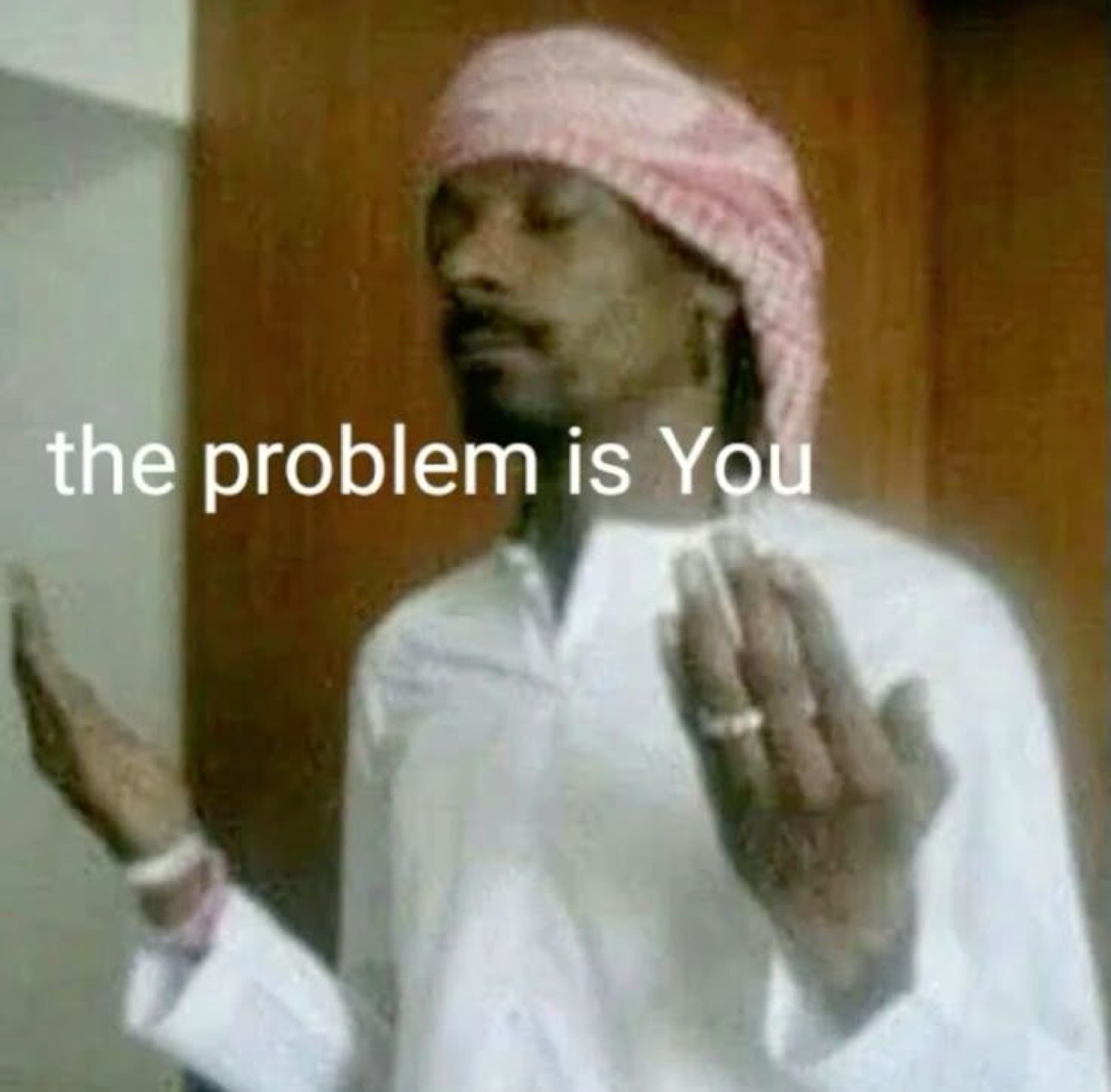 Man in a pink head wrap gesturing with raised hands, captioned 'the problem is You'