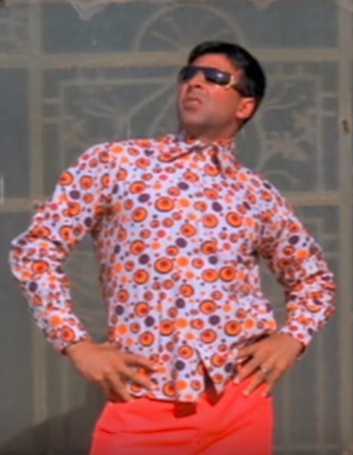 Akshay Kumar in a loud shirt and shades, hands on hips, looking away
