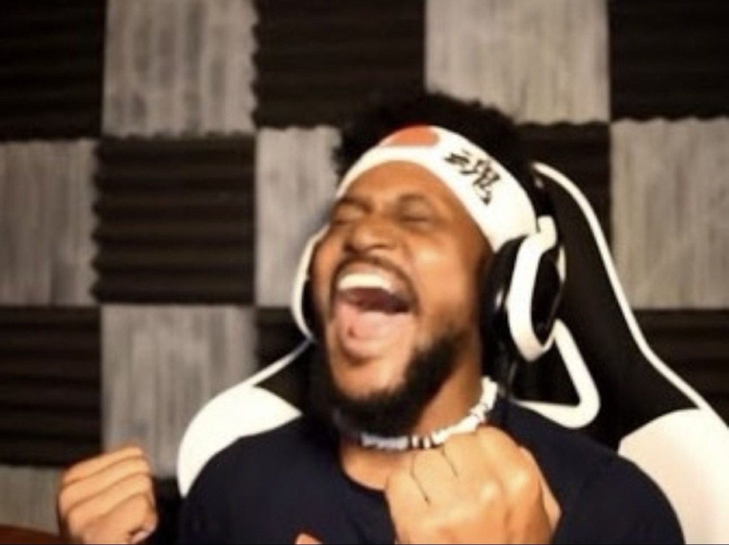 Man in a headband and headphones cheering with fists clenched and mouth wide open