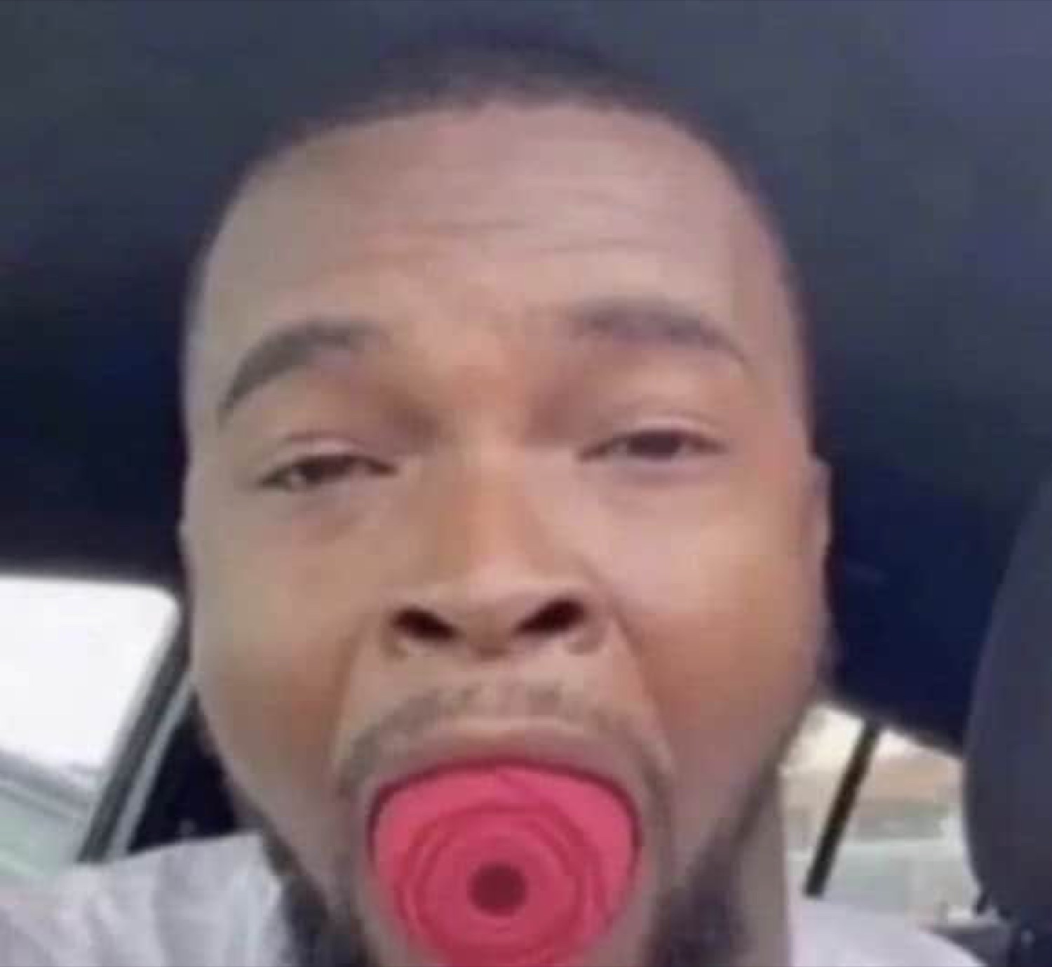 Man in the car with a red pacifier in his mouth staring at you with pure dead-eyed exhaustion