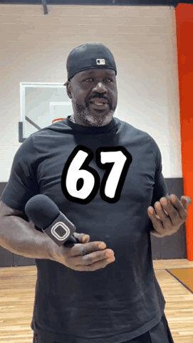 Man in a black 67 shirt in a gym doing the six seven hand gesture