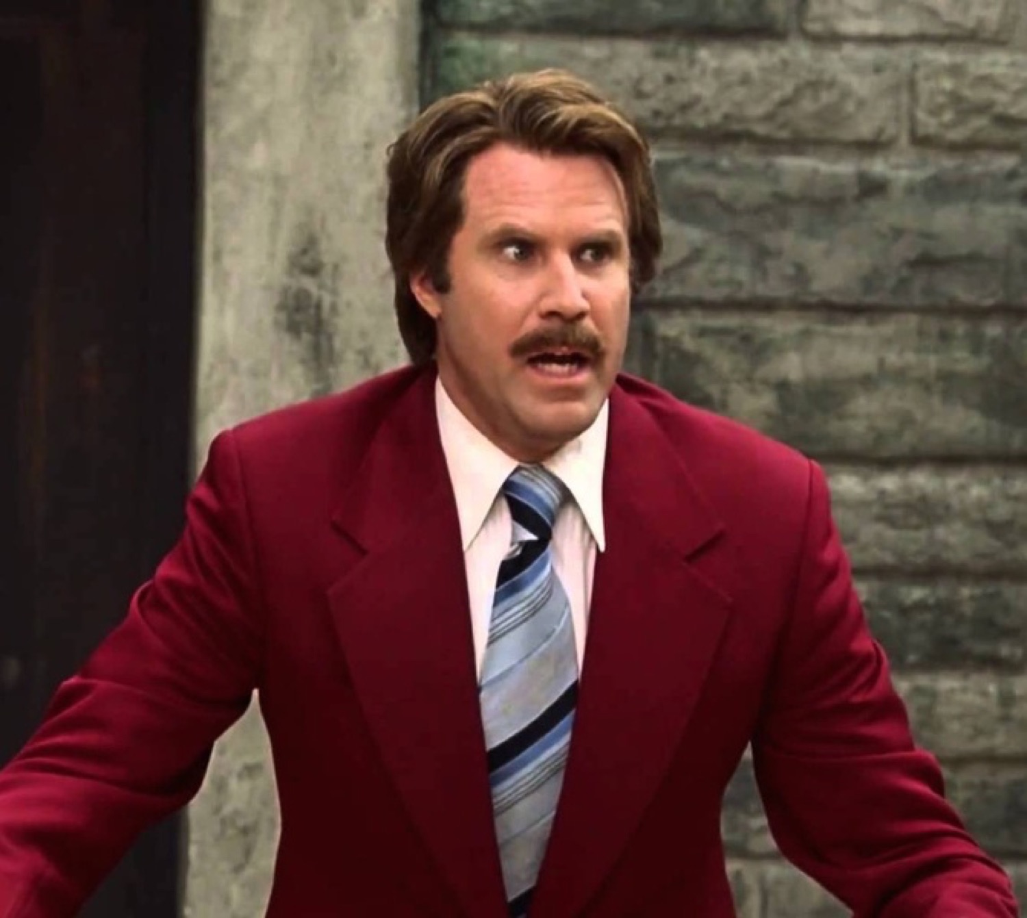 Will Ferrell as Ron Burgundy in a red suit with wide startled eyes and an open mouth