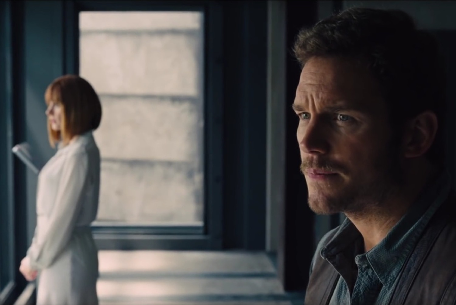 Chris Pratt looking quietly pained while someone else stands turned away in the background