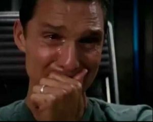 Man sobbing with tears streaming down his face, hand pressed to his mouth