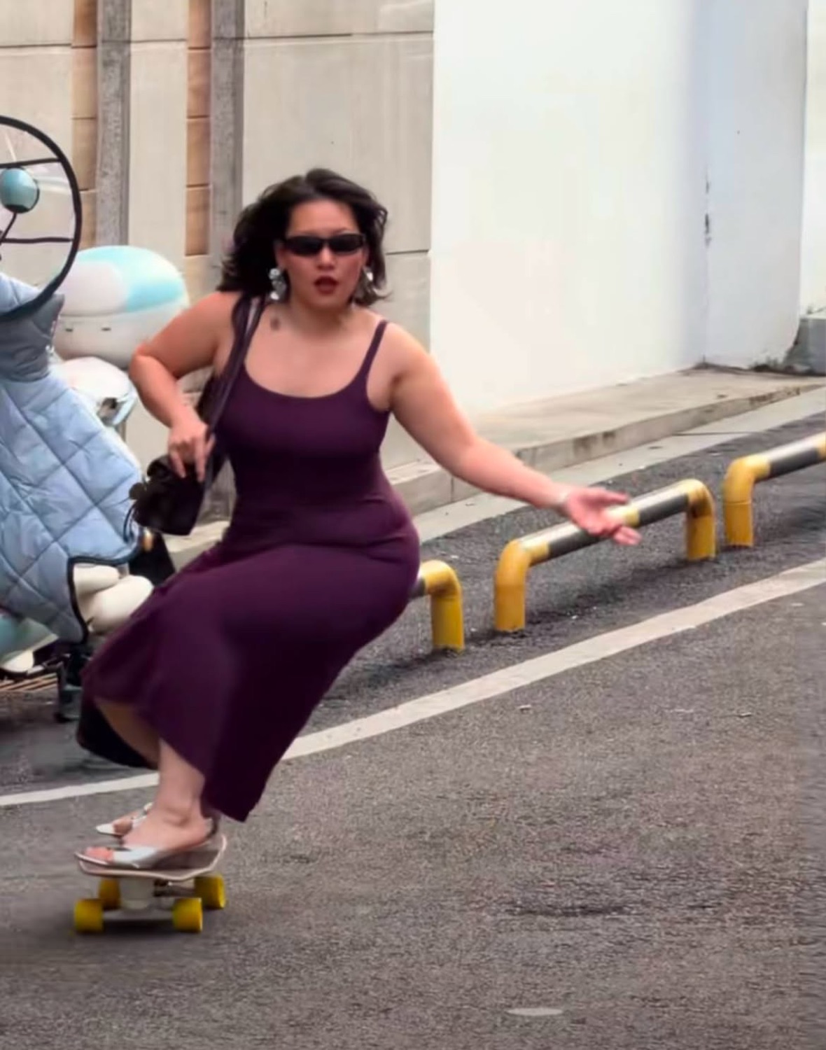 Woman in sunglasses riding a skateboard sitting down