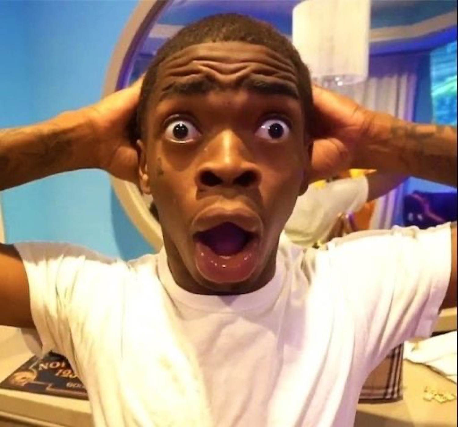 Young man gripping his head with a wide-open mouth in total shock