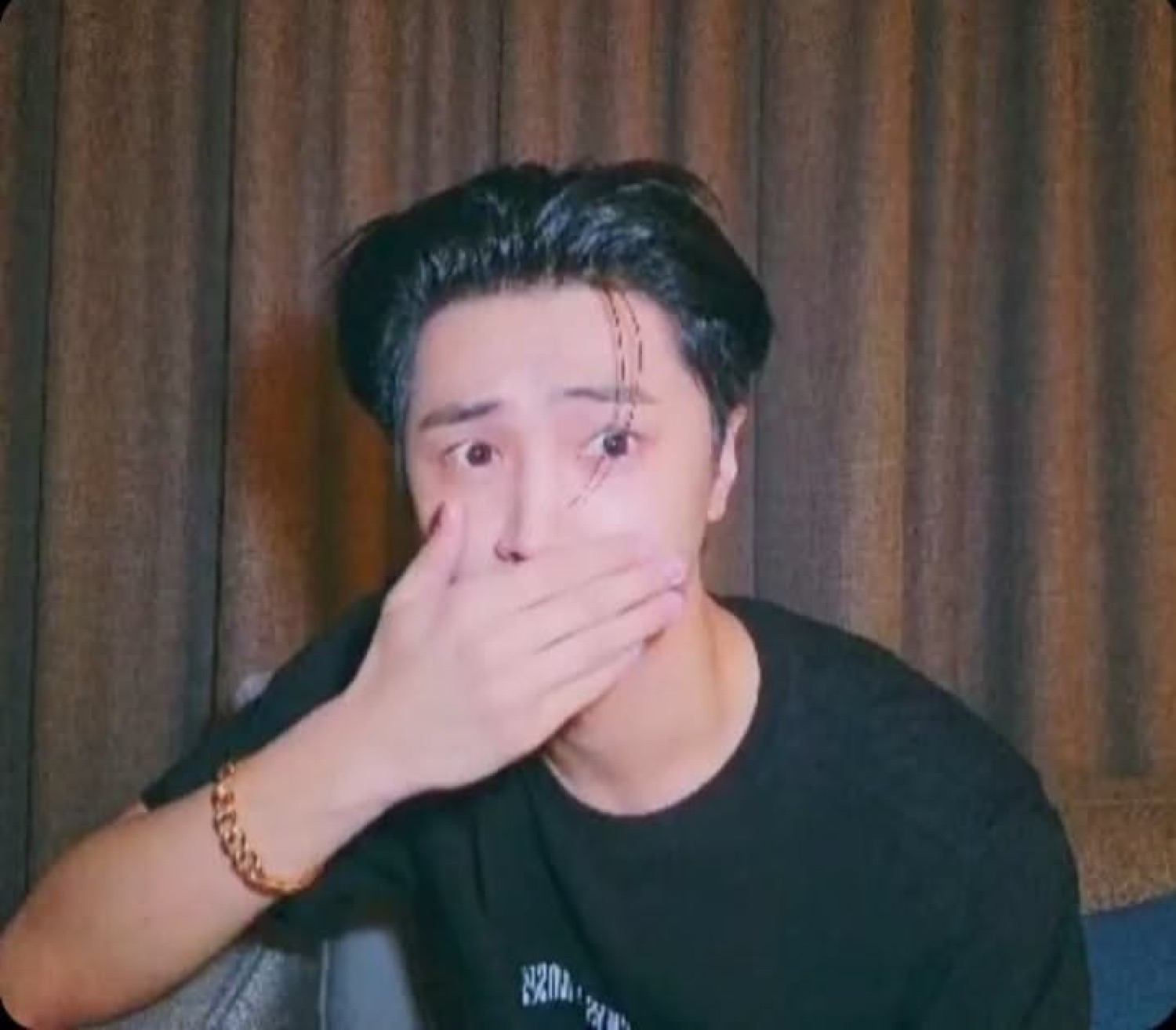 Guy covering his mouth with wide eyes in shock, hand raised to face