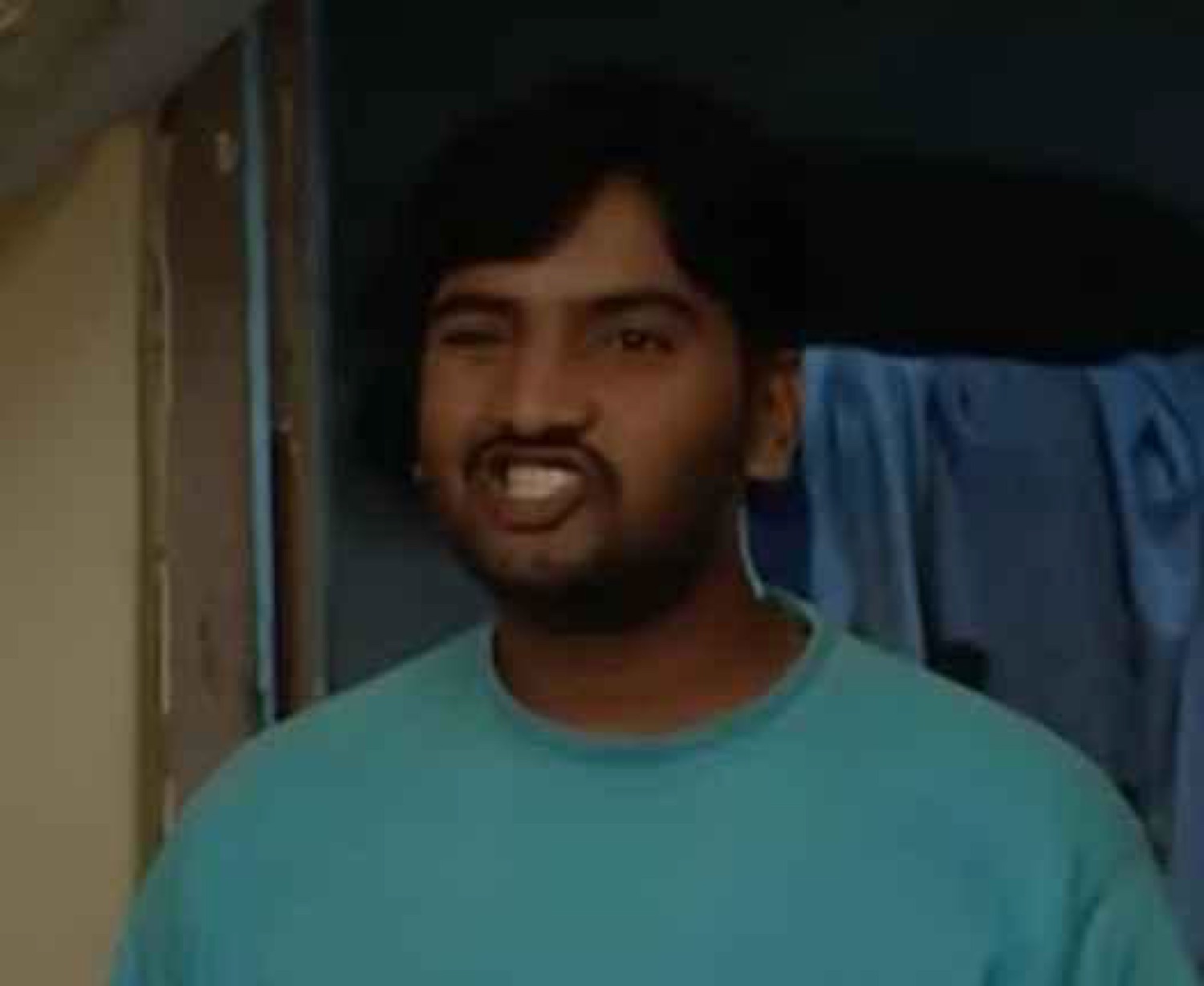 Guy in a teal shirt grinning mischievously