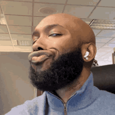 Bearded man in earbuds pursing his lips with a skeptical look