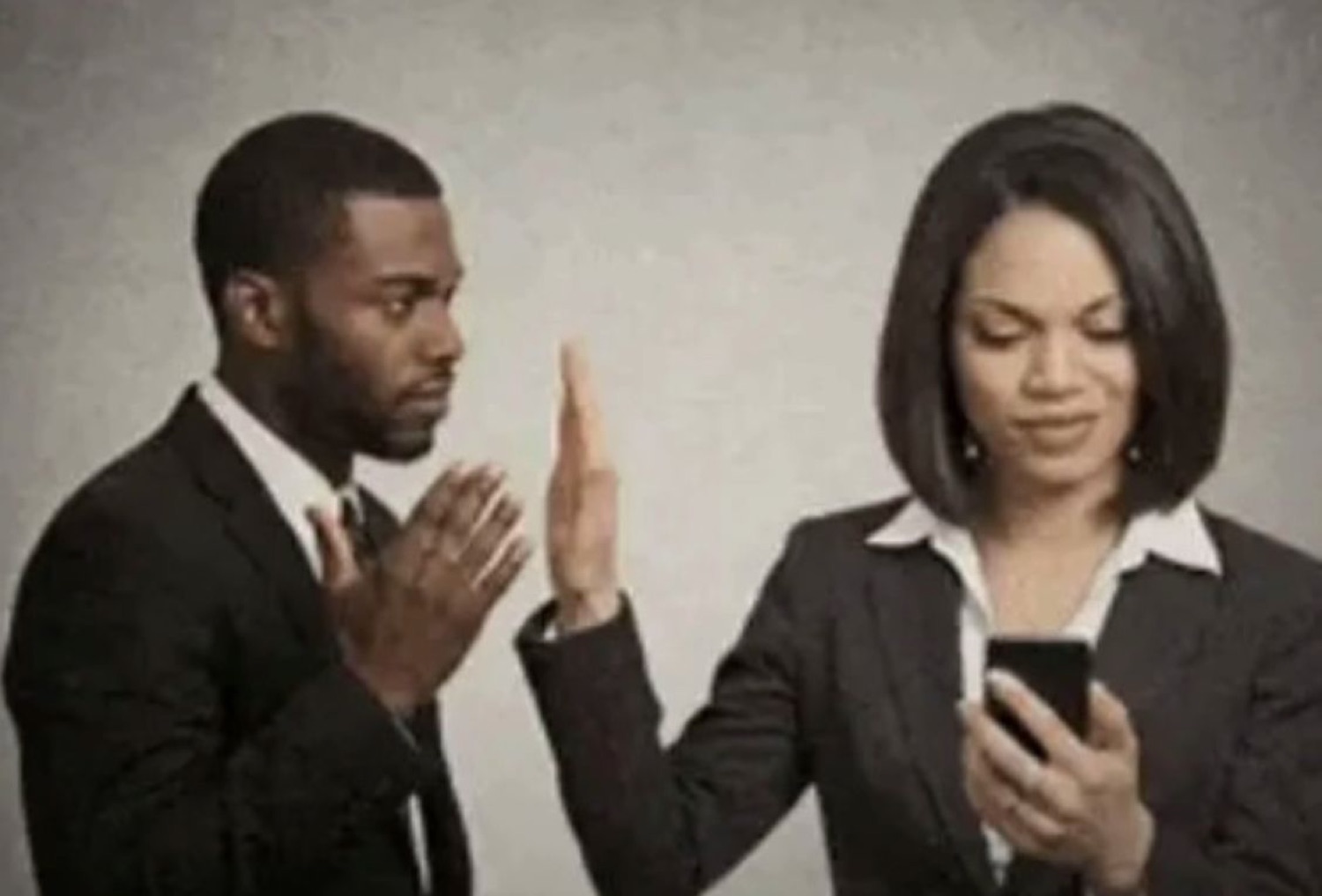 Woman on her phone holding up a hand to stop a man mid-plea
