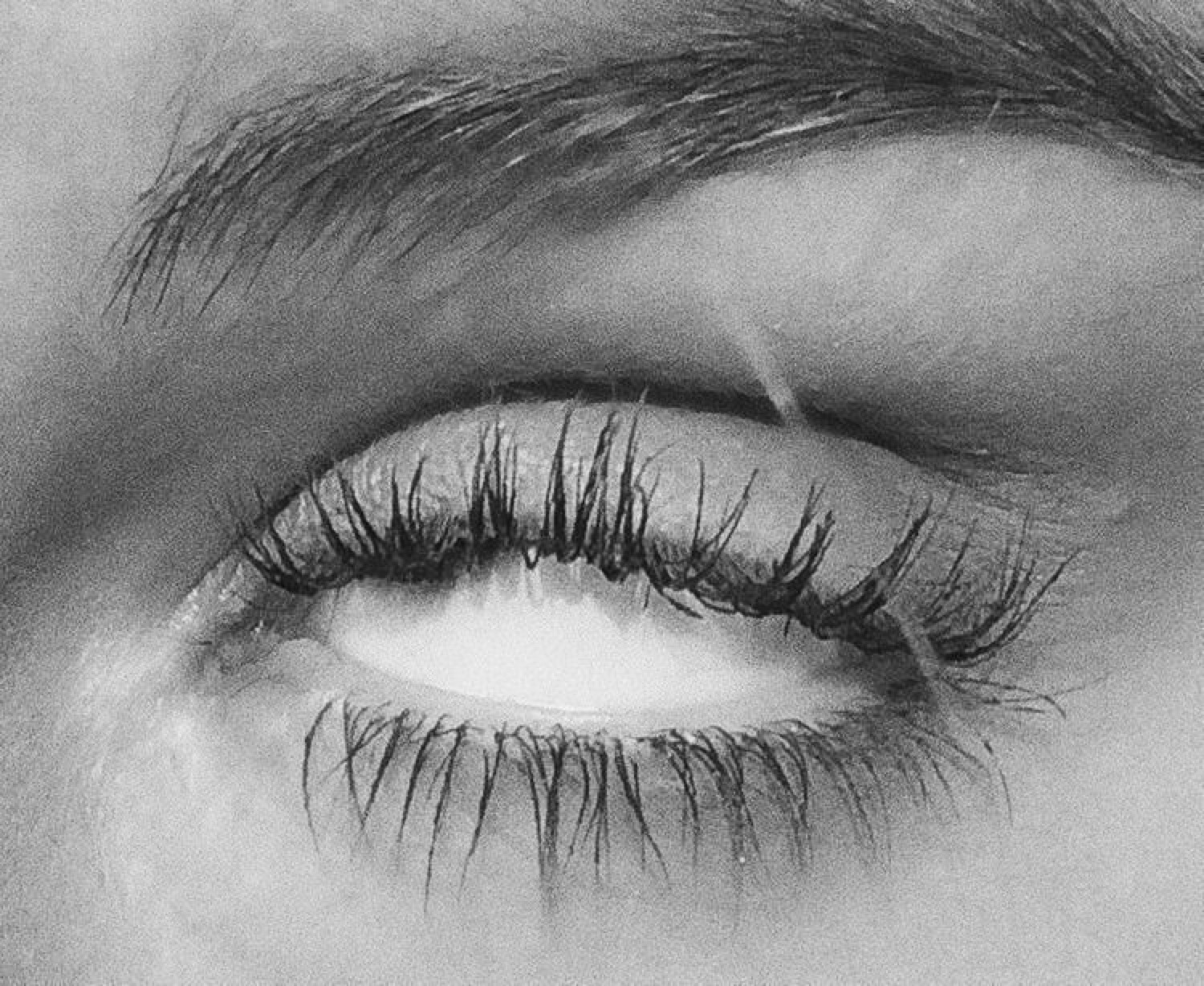 Extreme black-and-white close-up of a teary eye with long lashes