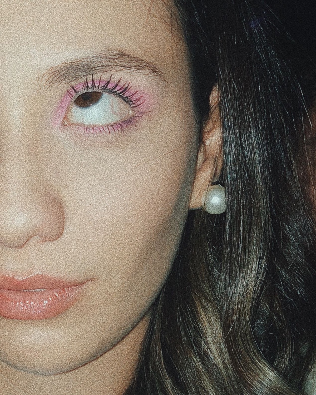 Close-up of a woman's face with pink eye shadow giving a half-lidded side-eye