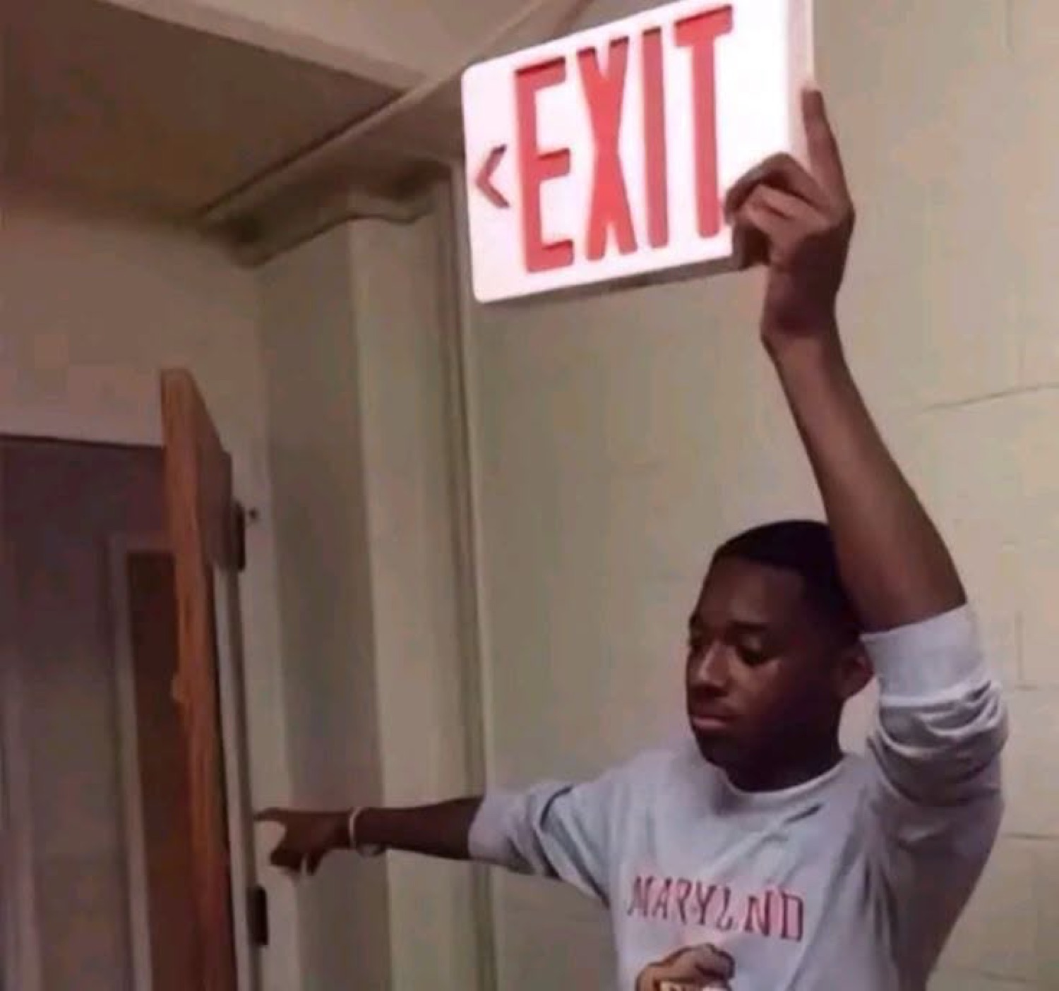 Man pointing at an EXIT sign held over the door