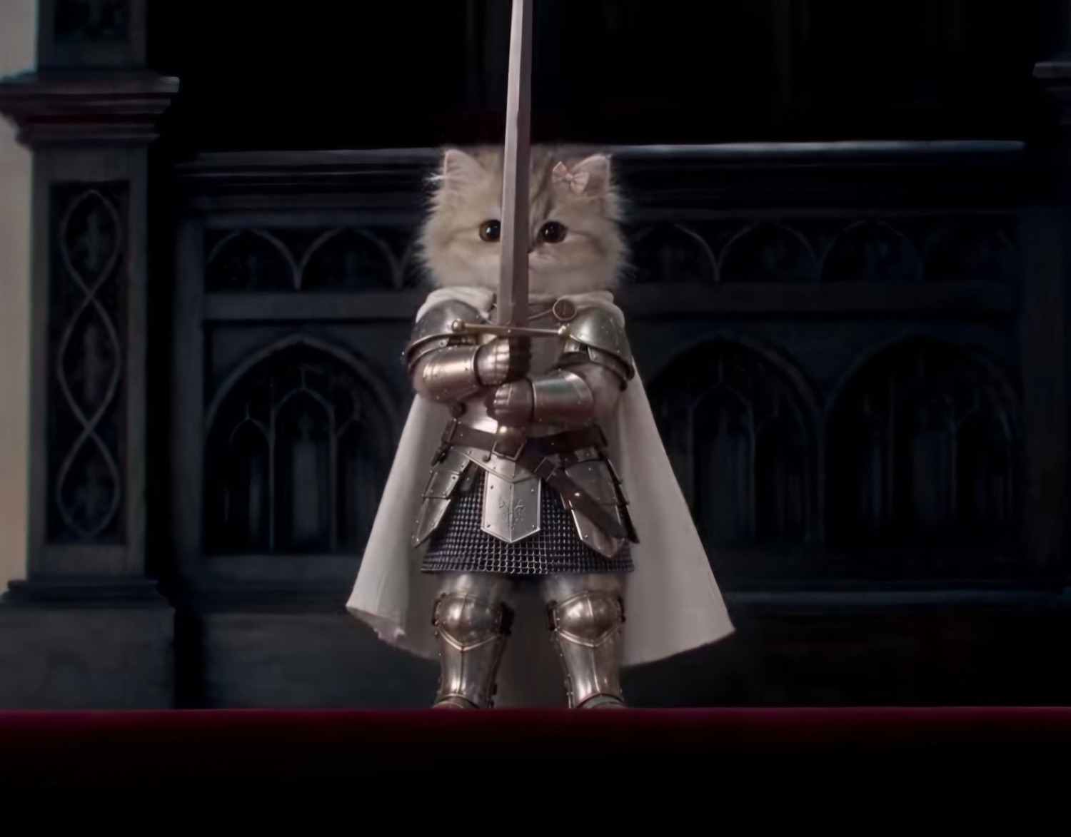 Tiny kitten in full plate armor holding a sword upright in a dark cathedral