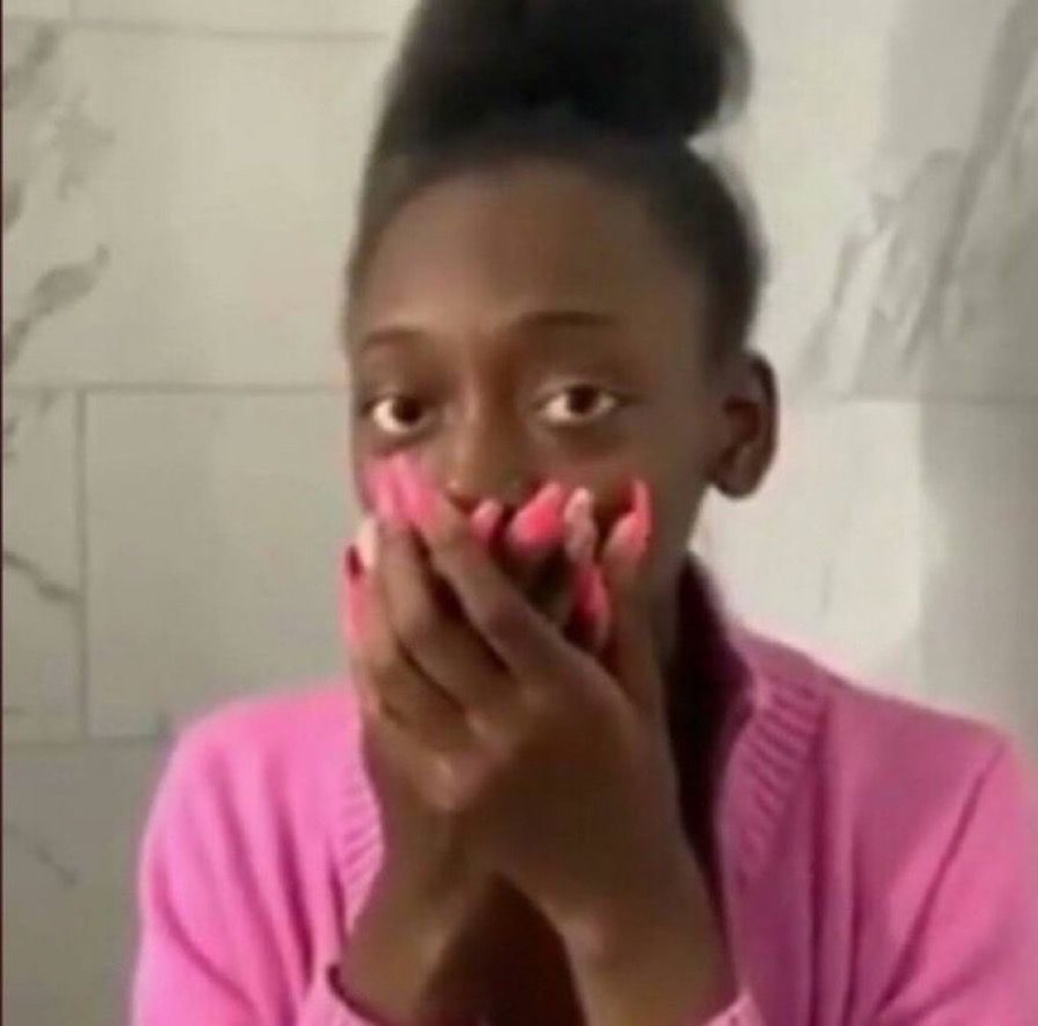 Girl in pink covering her mouth with both hands in shock