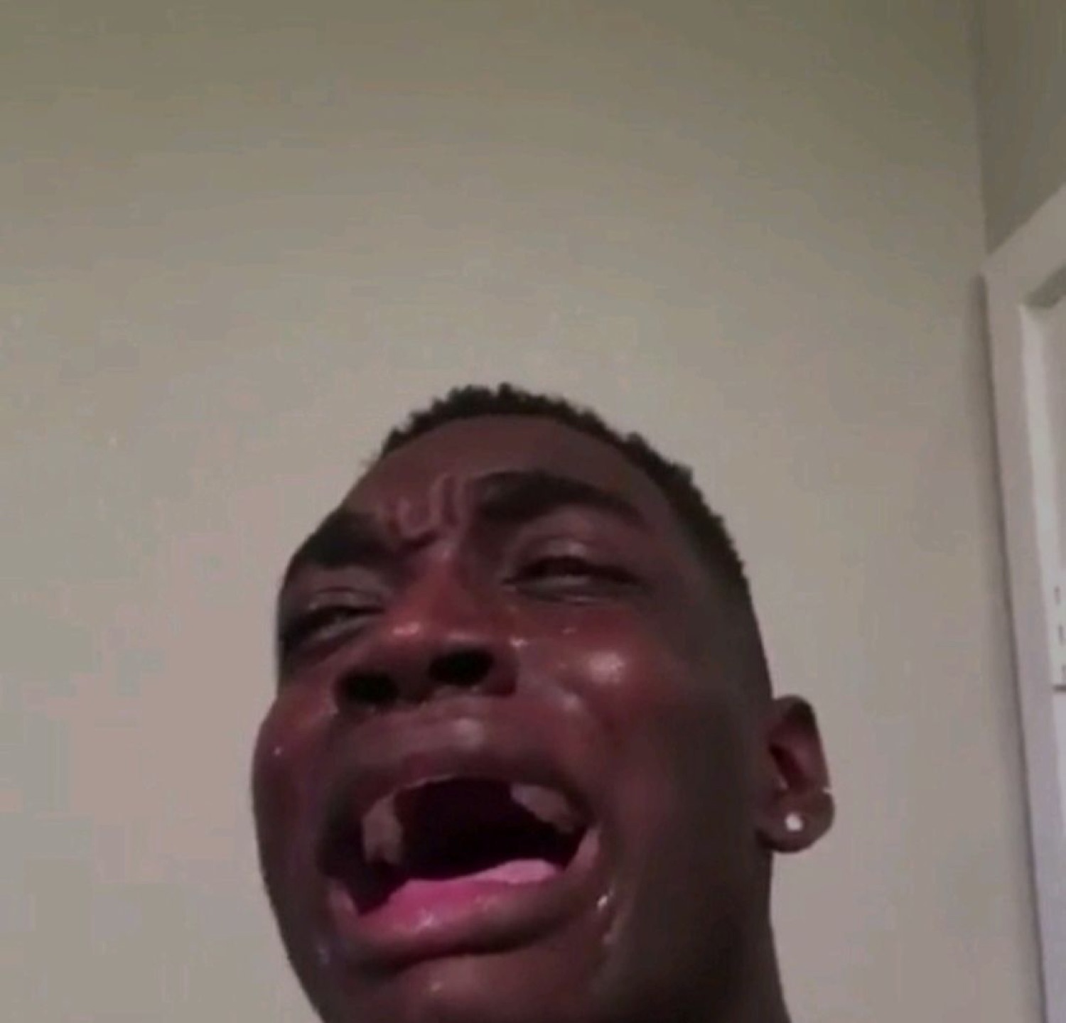 Young man sobbing hard with his mouth wide open and tears streaming down his face