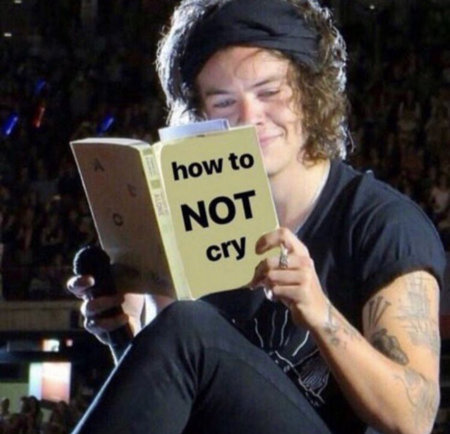 Harry Styles reading a book titled 'how to NOT cry' with a pained smile