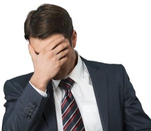Businessman in a suit and tie covering his face with his hand in exasperation