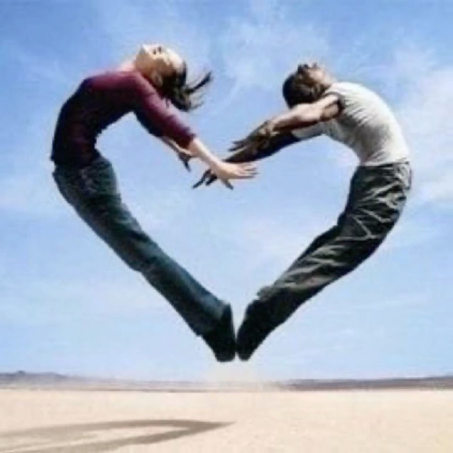 Two people leaping toward each other to form a heart shape in the sky