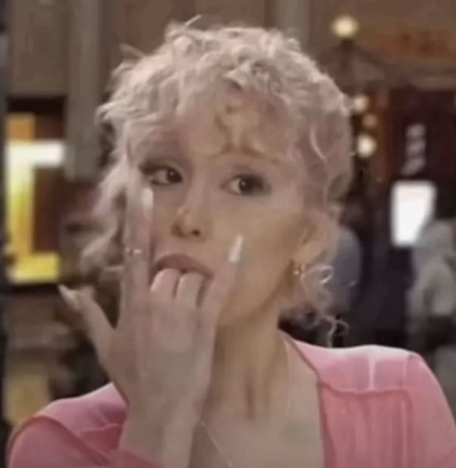 Blonde woman chewing on her finger with wide, panicked eyes