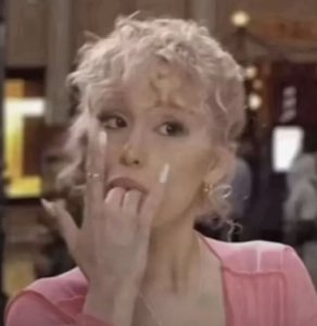Blonde woman chewing on her finger with wide, panicked eyes