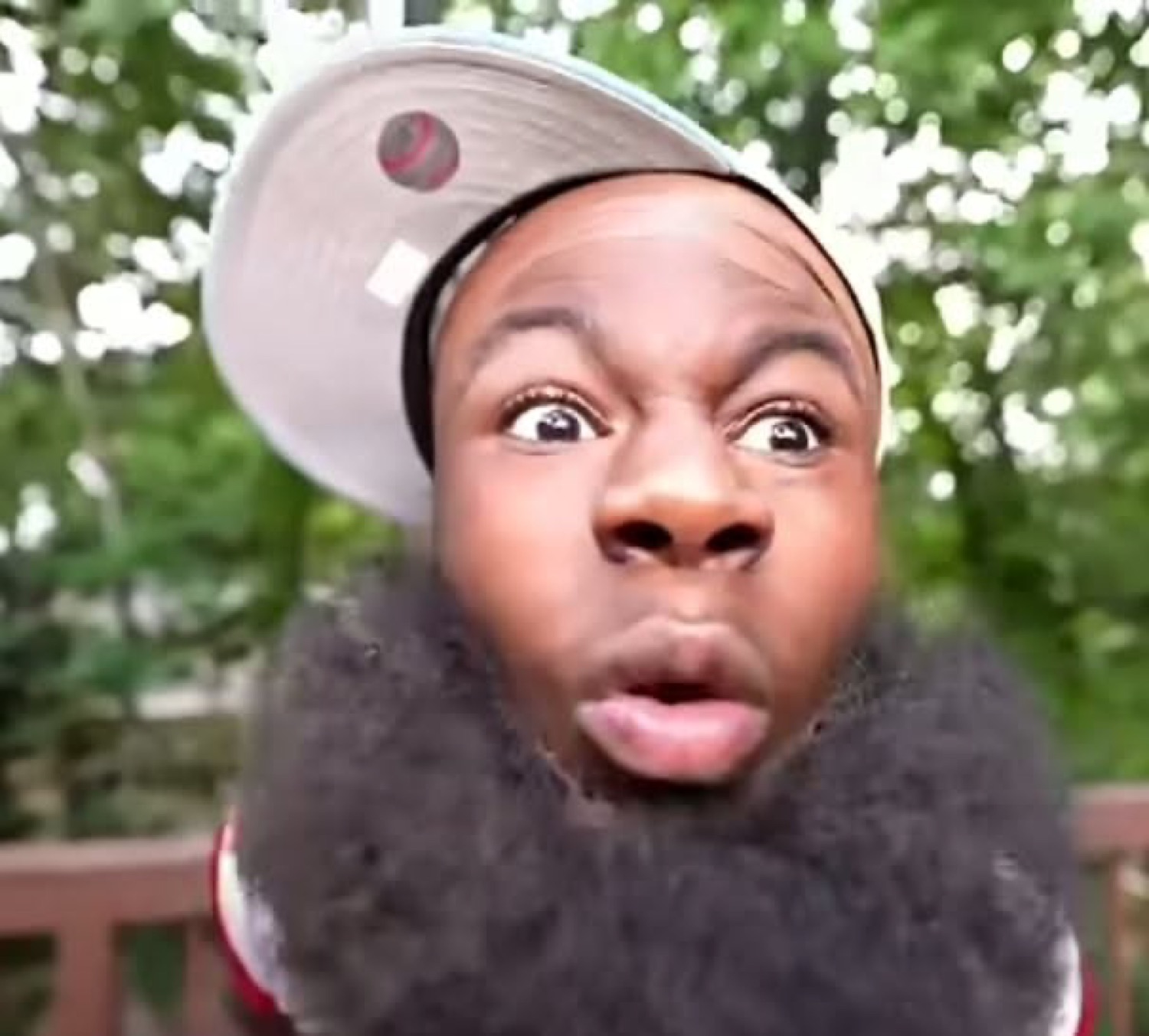 Guy in a backwards cap leaning into the camera with wide eyes and a shocked pucker