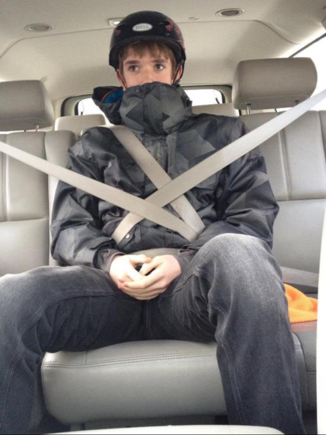 Guy in a car with two seatbelts strapped across him in an X