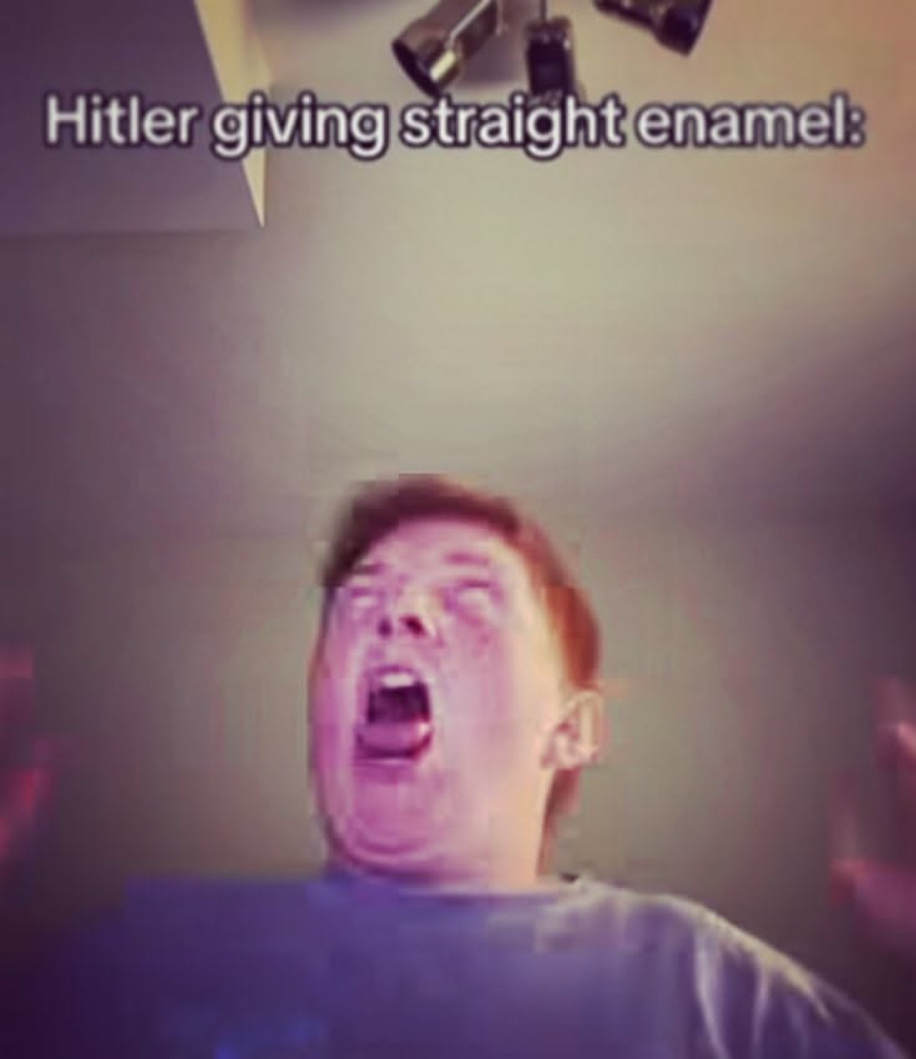Man tilted back howling with his eyes shut under a bright overhead lamp