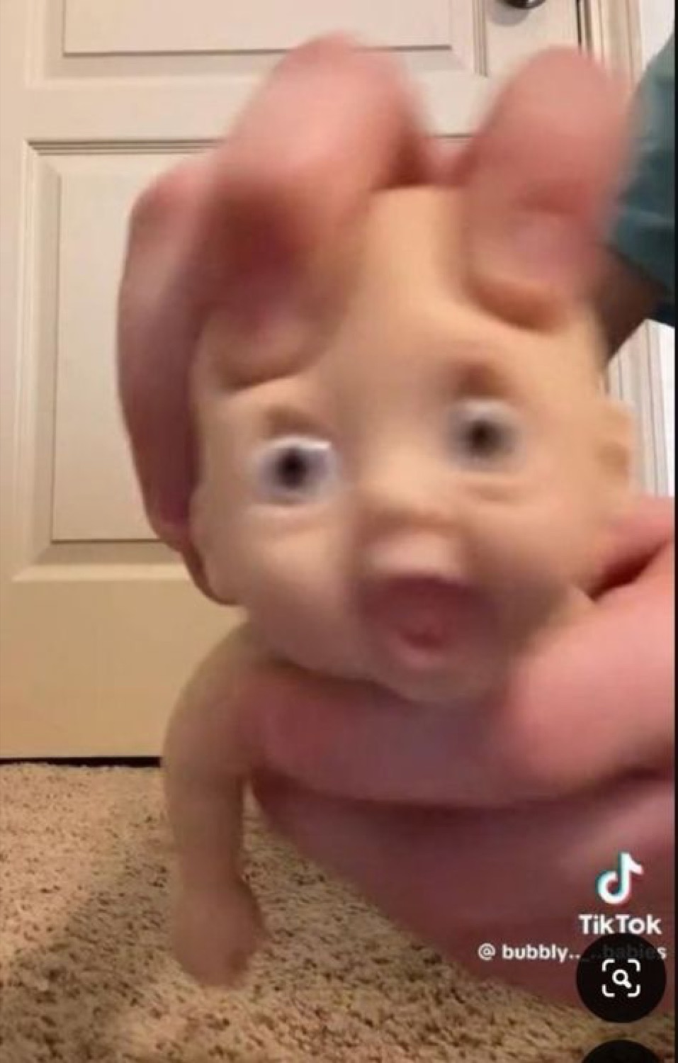 Hand squeezing a rubber baby doll whose eyes bulge in pure horror