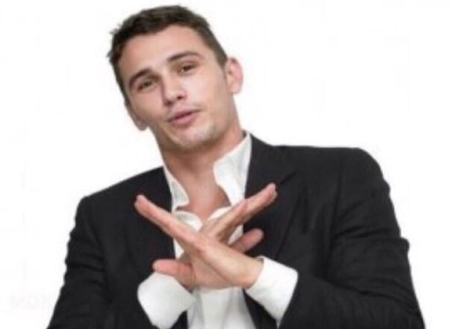 James Franco crossing his hands in an X with a smile