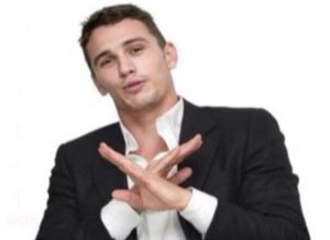 James Franco crossing his hands in an X with a smile