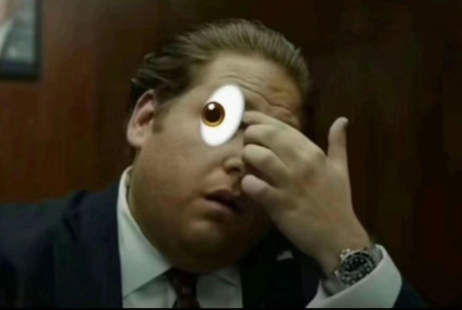 Man in a suit with a huge cartoon googly eye pasted over his face, looking stunned