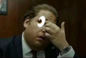 Man in a suit with a huge cartoon googly eye pasted over his face, looking stunned